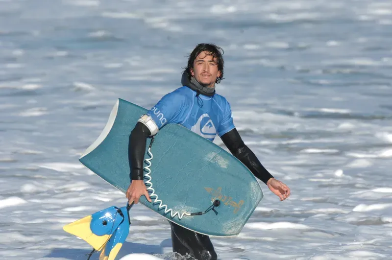Jeune bodyboarder sortant de l'eau avec son bodyboard et ses palmes à Capbreton