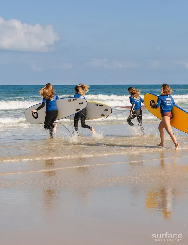 Élèves du Santocha courant vers les vagues avec leurs planches de surf à Capbreton