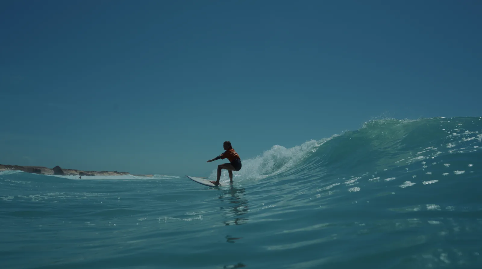 Surfeuse en lycra orange sur les vagues de Capbreton